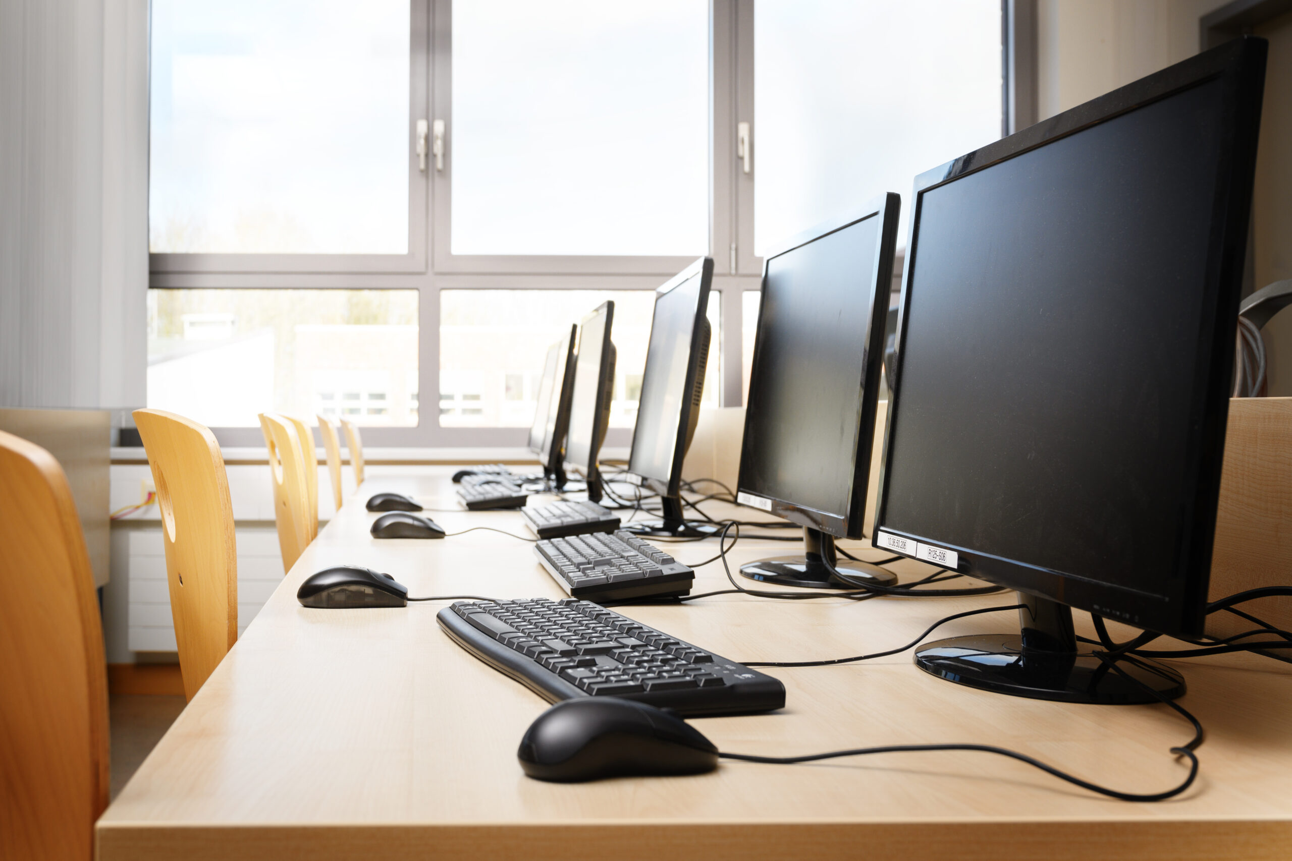 Empty computer room with monitors and keyboards in a row for pupils and students in a school computer lab, selected focus, narrow depth of field